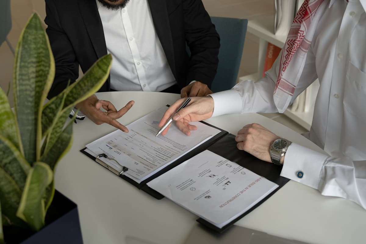اجتماع عمل يراجع فيه طرفان تفاصيل مشروع ومستنداته على طاولة المكتب