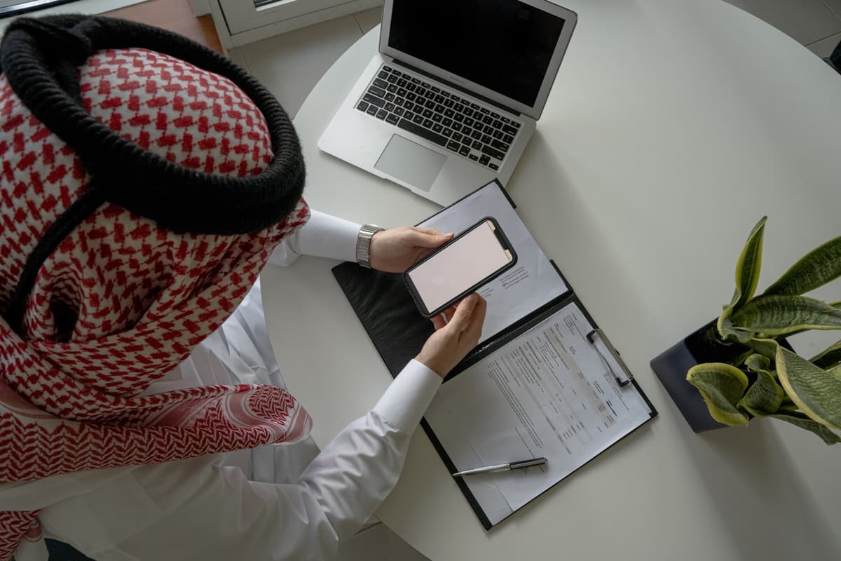 رجل أعمال سعودي يتابع أعماله من الحاسب المحمول والجوال في مكتبه